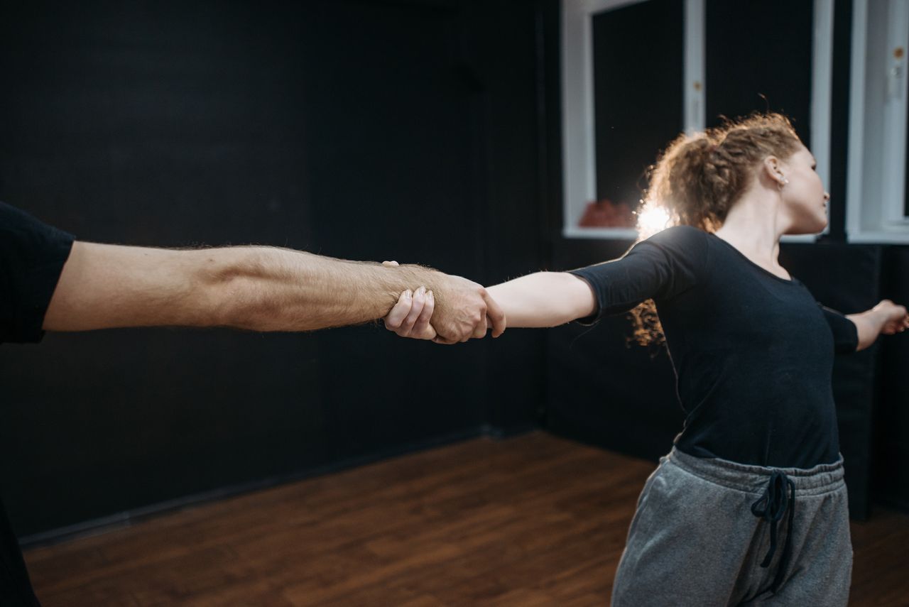 A young couple practicing dance moves indoors, focusing on coordination and precision.